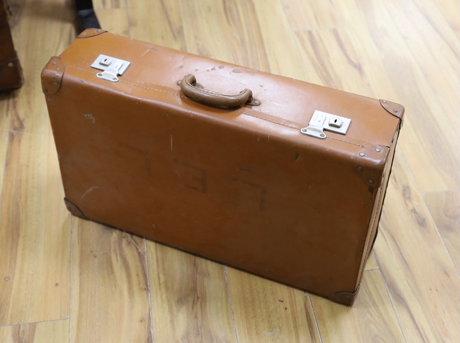 Three early 20th century brown leather cabin trunks and a later vintage suitcase, largest trunk 92cms wide x 52cms deep